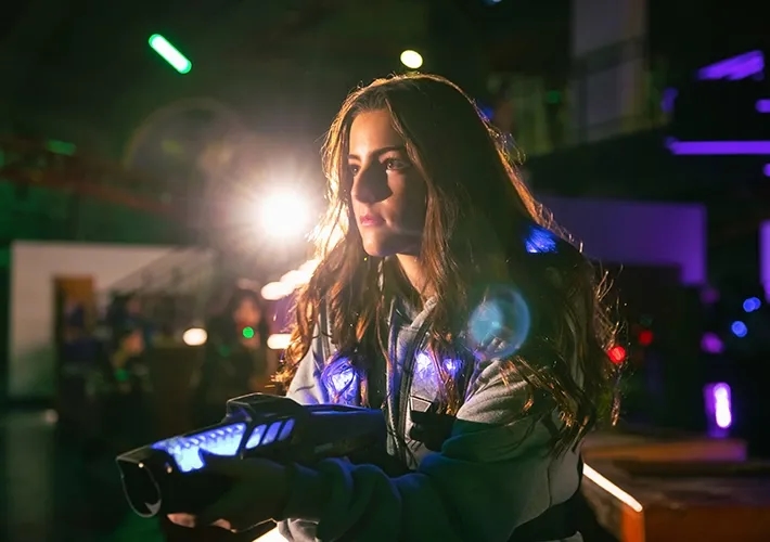 Female character aiming a troca laser gadget with blue illumination