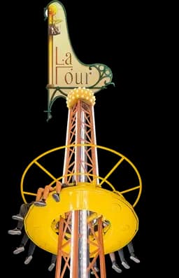 A vertical drop tower amusement ride called "La Tour" with a yellow circular seating gondola and riders' legs visible.